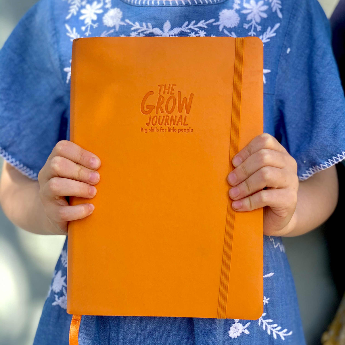 Girl holding The Grow Journal, gratitude journal for kids